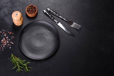 Bıçak ve çatalla arka planda boş gri bir plaka.