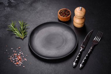 Bıçak ve çatalla arka planda boş gri bir plaka.