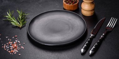 Empty gray plate on a dark background with a knife and fork