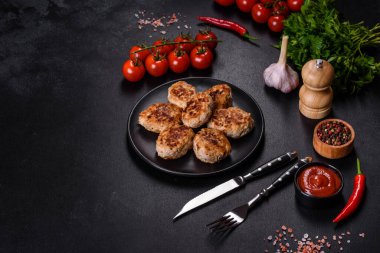 Kızartma tavasında kıymalı pirzola ve koyu beton zeminde baharatlar.