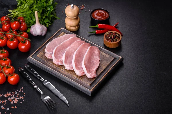 stock image Raw fresh pork meat sliced on a wooden cutting board against a dark concrete background