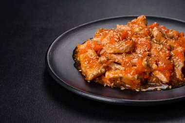 Soslu teriyaki tavuğu, susam, otlar ve baharatlar koyu beton arka planda. Asya mutfağı