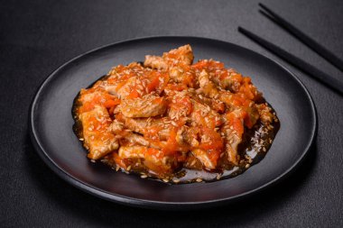 Soslu teriyaki tavuğu, susam, otlar ve baharatlar koyu beton arka planda. Asya mutfağı