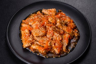 Soslu teriyaki tavuğu, susam, otlar ve baharatlar koyu beton arka planda. Asya mutfağı