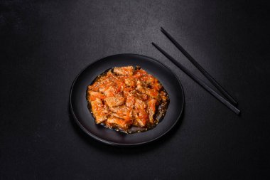 Soslu teriyaki tavuğu, susam, otlar ve baharatlar koyu beton arka planda. Asya mutfağı