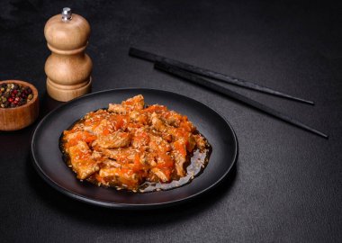 Soslu teriyaki tavuğu, susam, otlar ve baharatlar koyu beton arka planda. Asya mutfağı
