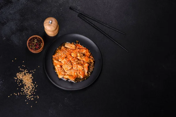 Soslu teriyaki tavuğu, susam, otlar ve baharatlar koyu beton arka planda. Asya mutfağı