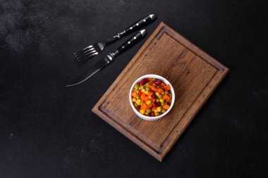 Kesilmiş sebze, kırmızı biber, mısır ve bezelye karışımı koyu beton bir arka planda.