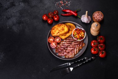 Lezzetli ızgara pastırma dilimleri, baharatlı, tuzlu, sebzeli ve çimento kaplı arka planda kızartılmış yumurta ve kızarmış ekmek.