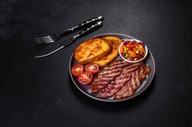 Lezzetli ızgara pastırma dilimleri, baharatlı, tuzlu, sebzeli ve çimento kaplı arka planda kızartılmış yumurta ve kızarmış ekmek.