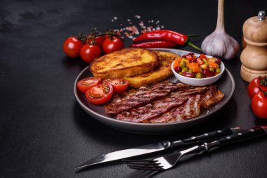 Lezzetli ızgara pastırma dilimleri, baharatlı, tuzlu, sebzeli ve çimento kaplı arka planda kızartılmış yumurta ve kızarmış ekmek.