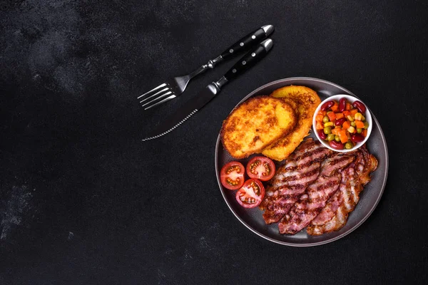 Lezzetli ızgara pastırma dilimleri, baharatlı, tuzlu, sebzeli ve çimento kaplı arka planda kızartılmış yumurta ve kızarmış ekmek.