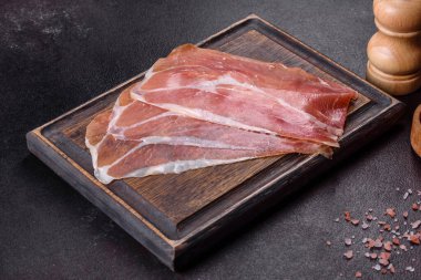 İtalyan jambonu ya da İspanyol jamonu. Koyu renk kesim tahtasında tuz ve baharatla.