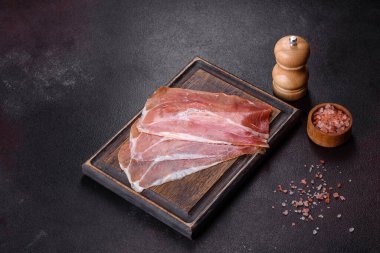 İtalyan jambonu ya da İspanyol jamonu. Koyu renk kesim tahtasında tuz ve baharatla.