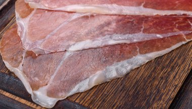 İtalyan jambonu ya da İspanyol jamonu. Koyu renk kesim tahtasında tuz ve baharatla.