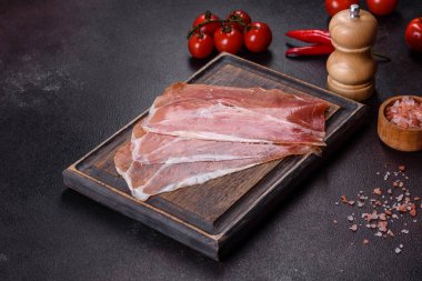 İtalyan jambonu ya da İspanyol jamonu. Koyu renk kesim tahtasında tuz ve baharatla.