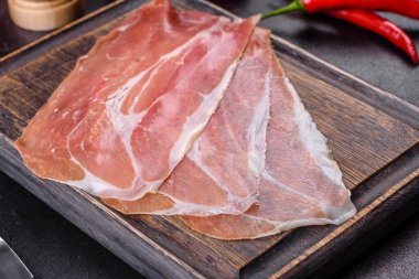 İtalyan jambonu ya da İspanyol jamonu. Koyu renk kesim tahtasında tuz ve baharatla.