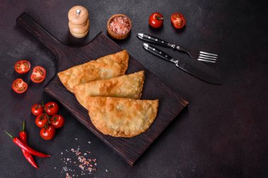 Cheburek etli börek ve şifalı otlar. Siyah beton arka plan. Üst görünüm