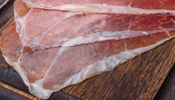İtalyan jambonu ya da İspanyol jamonu. Koyu renk kesim tahtasında tuz ve baharatla.