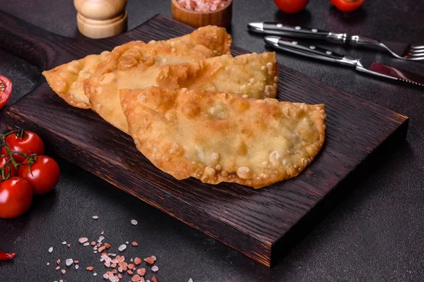 Cheburek etli börek ve şifalı otlar. Siyah beton arka plan. Üst görünüm