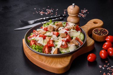 Çeri domatesli taze sebze salatası, salatalık, ekmek kırıntıları ve koyu beton arkaplanda parmesan peyniri.
