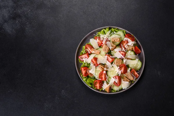 Çeri domatesli taze sebze salatası, salatalık, ekmek kırıntıları ve koyu beton arkaplanda parmesan peyniri.