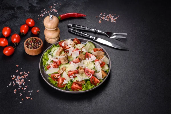 Çeri domatesli taze sebze salatası, salatalık, ekmek kırıntıları ve koyu beton arkaplanda parmesan peyniri.