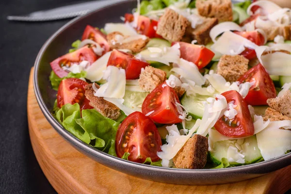 Çeri domatesli taze sebze salatası, salatalık, ekmek kırıntıları ve koyu beton arkaplanda parmesan peyniri.
