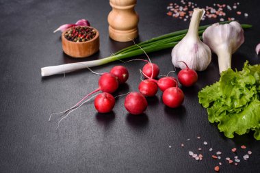 Tahta kesme tahtasında koyu beton zemine karşı bahar salatası yapmak için malzeme olarak lezzetli taze kırmızı turp.