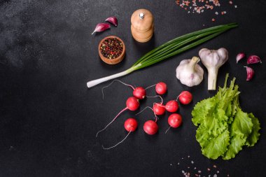 Tahta kesme tahtasında koyu beton zemine karşı bahar salatası yapmak için malzeme olarak lezzetli taze kırmızı turp.