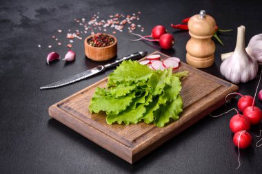 Taze, lezzetli marul yaprakları ahşap kesim tahtasının üzerinde koyu beton bir zemine karşı.