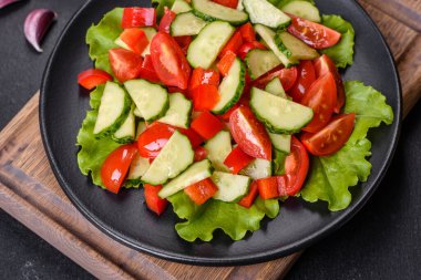 Marul, salatalık, ıspanak, domates ve bıldırcın yumurtası otlu salata ve siyah bir tabakta limon.