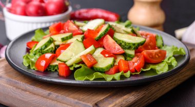 Marul, salatalık, ıspanak, domates ve bıldırcın yumurtası otlu salata ve siyah bir tabakta limon.