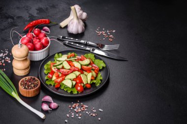 Marul, salatalık, ıspanak, domates ve bıldırcın yumurtası otlu salata ve siyah bir tabakta limon.