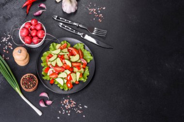 Marul, salatalık, ıspanak, domates ve bıldırcın yumurtası otlu salata ve siyah bir tabakta limon.