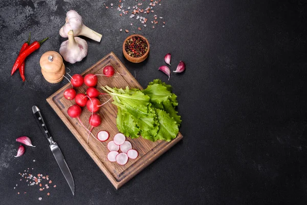 Taze, lezzetli marul yaprakları ahşap kesim tahtasının üzerinde koyu beton bir zemine karşı.