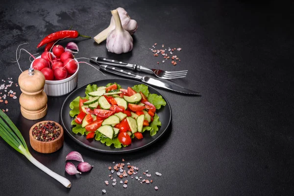 Marul, salatalık, ıspanak, domates ve bıldırcın yumurtası otlu salata ve siyah bir tabakta limon.