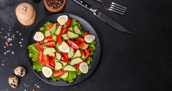 Marul, salatalık, ıspanak, domates ve bıldırcın yumurtası otlu salata ve siyah bir tabakta limon.