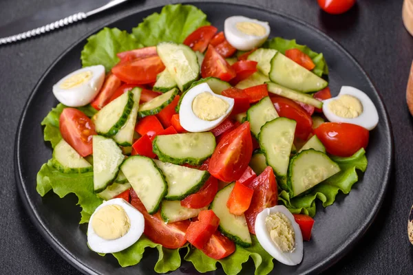 Marul, salatalık, ıspanak, domates ve bıldırcın yumurtası otlu salata ve siyah bir tabakta limon.