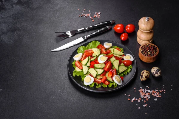 Marul, salatalık, ıspanak, domates ve bıldırcın yumurtası otlu salata ve siyah bir tabakta limon.