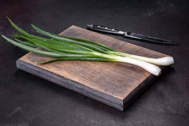 Kesme tahtasındaki soğan soğanlarını kes. Koyu beton arkaplan