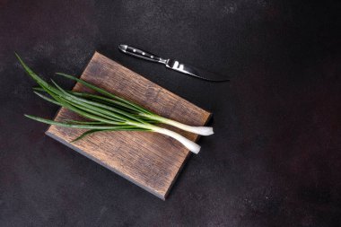 Kesme tahtasındaki soğan soğanlarını kes. Koyu beton arkaplan