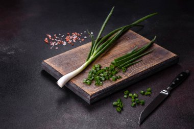 Kesme tahtasındaki soğan soğanlarını kes. Koyu beton arkaplan