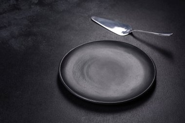 Siyah arka planda boş siyah plaka, çatal ve bıçak. Üst görünüm, alanı kopyala