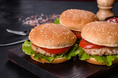Üç hamburger sığır eti burger ve koyu arka plan üzerinde taze sebze ile. Lezzetli yemekler