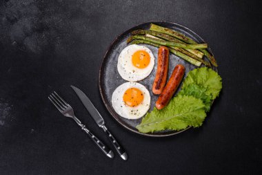 Yağda yumurta, sosis, kuşkonmaz, domates, avokado, baharat ve bitkilerle besleyici lezzetli bir kahvaltı. Güne enerjik bir başlangıç için uygun beslenme