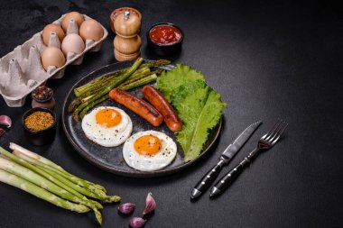 Yağda yumurta, sosis, kuşkonmaz, domates, avokado, baharat ve bitkilerle besleyici lezzetli bir kahvaltı. Güne enerjik bir başlangıç için uygun beslenme