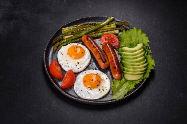Yağda yumurta, sosis, kuşkonmaz, domates, avokado, baharat ve bitkilerle besleyici lezzetli bir kahvaltı. Güne enerjik bir başlangıç için uygun beslenme