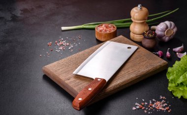 Et, baharat ve otlar için bir balta koyu beton arka planda bir kesim tahtası. Evde yemek pişirmek.