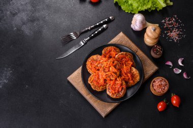 Köfte, domates sosu ve siyah tabakta otlar..